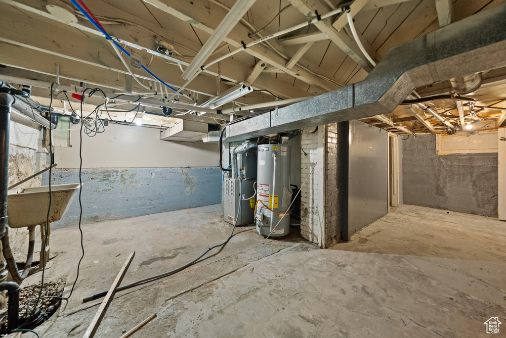Unfinished below grade area featuring gas water heater and heating unit
