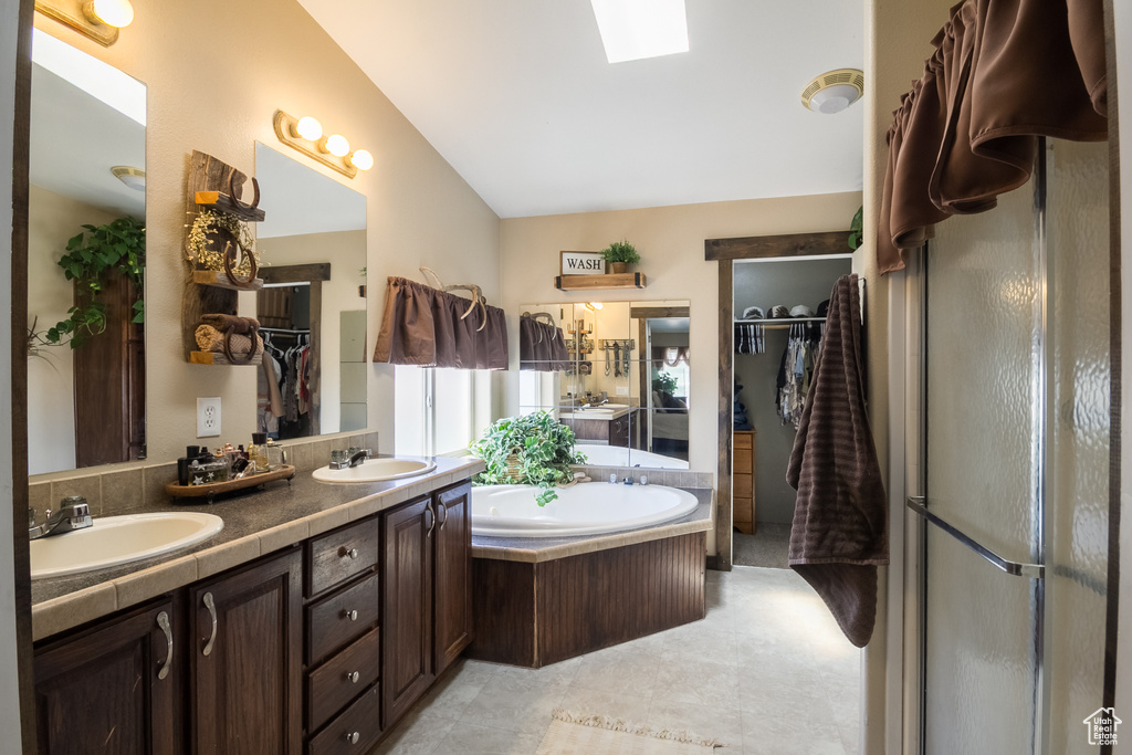 Bathroom featuring double vanity, a garden tub, a skylight, and a shower