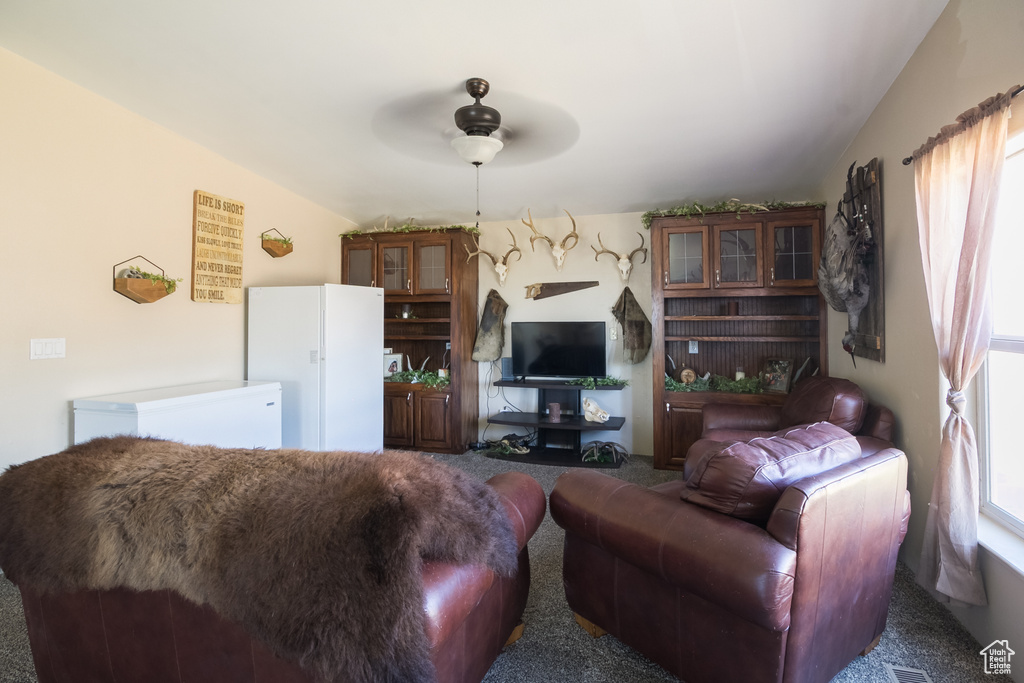 Carpeted living area featuring ceiling fan