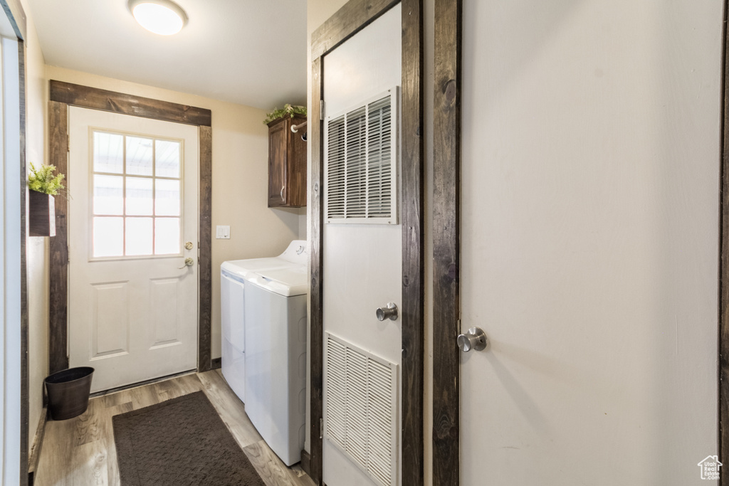 Washroom featuring cabinet space, independent washer and dryer, and light wood-style floors