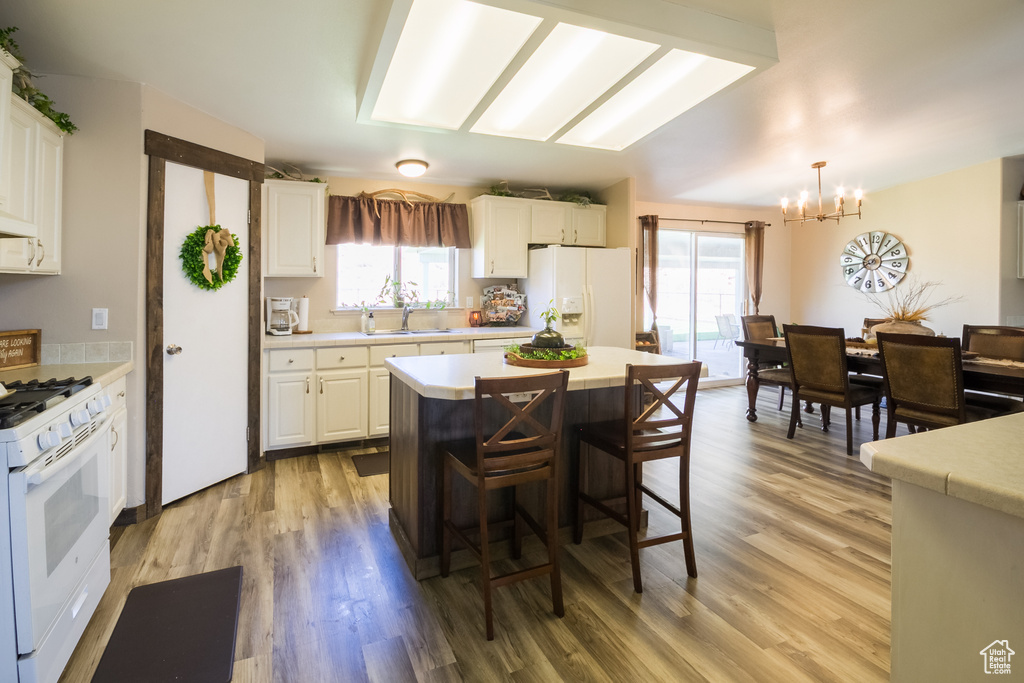 Kitchen featuring white appliances, a chandelier, light countertops, and plenty of natural light