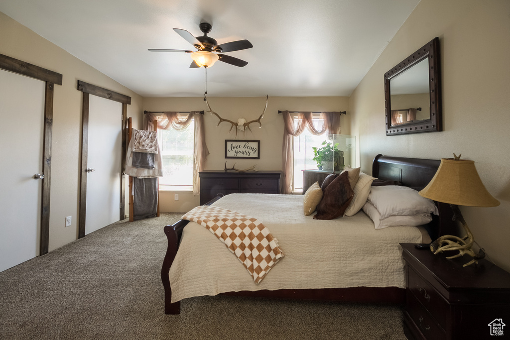 Bedroom with multiple windows, vaulted ceiling, carpet floors, and a ceiling fan