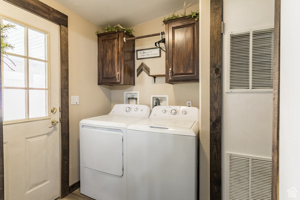 Laundry area with a heating unit, cabinet space, washer and dryer, and healthy amount of natural light