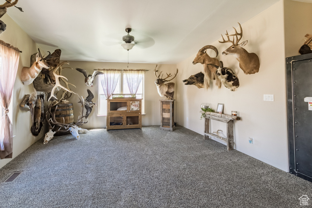 Miscellaneous room with a ceiling fan and carpet