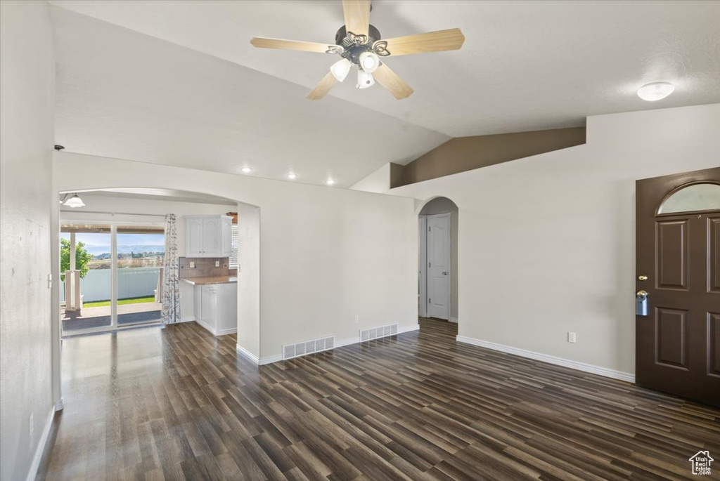 Unfurnished living room with arched walkways, lofted ceiling, dark wood-style flooring, ceiling fan, and recessed lighting