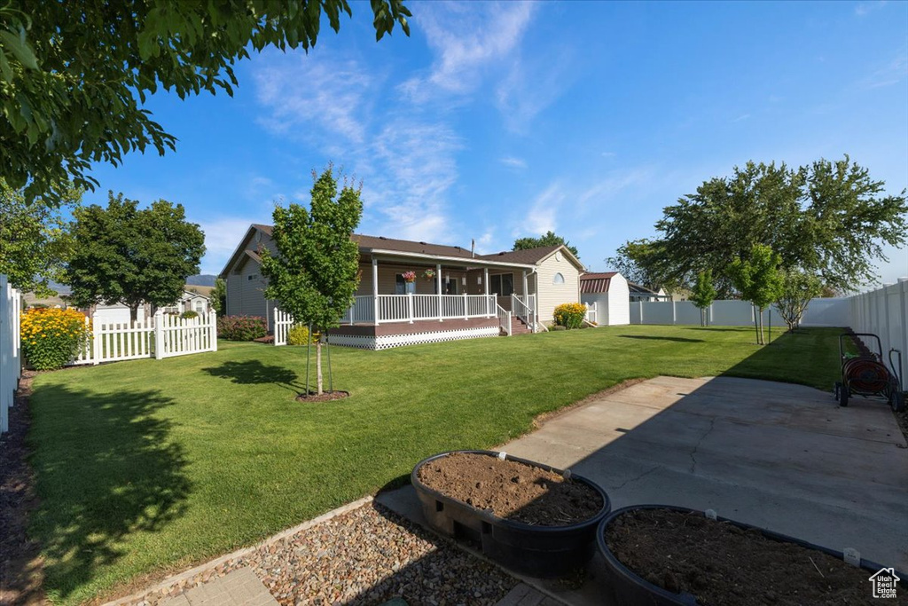 Back of house with a fenced backyard, covered porch, and a patio area
