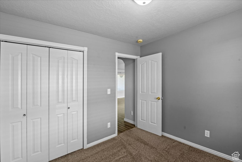 Unfurnished bedroom with a closet, carpet flooring, and a textured ceiling