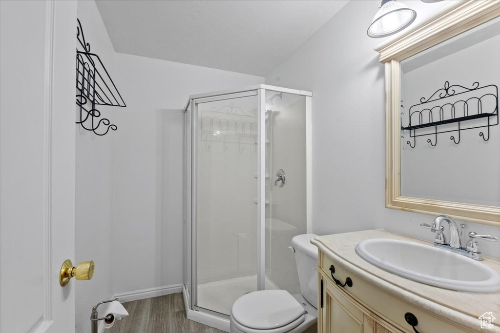 Full bath featuring a shower stall, vanity, and wood finished floors