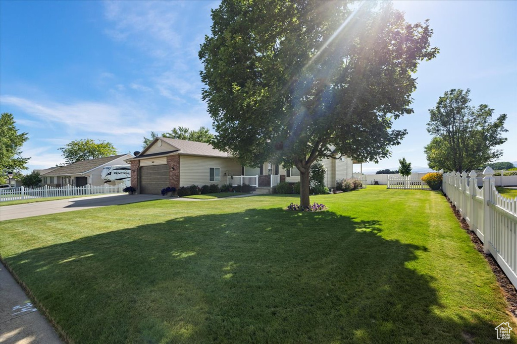 View of front of home with concrete driveway, an attached garage, and a fenced backyard