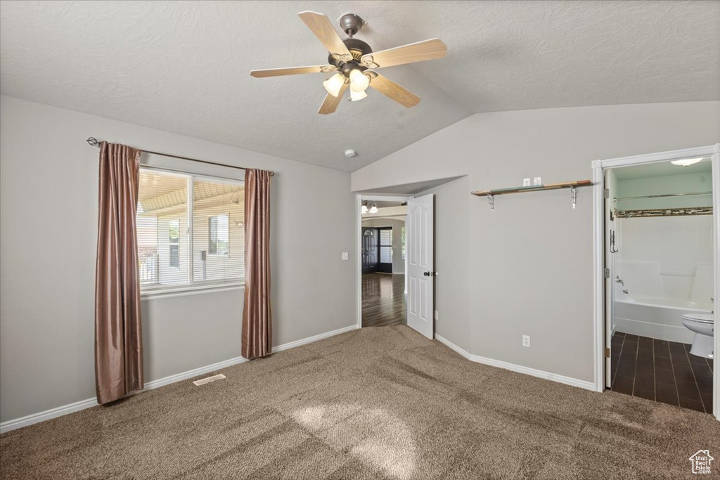 Unfurnished bedroom with carpet, lofted ceiling, a textured ceiling, a ceiling fan, and connected bathroom