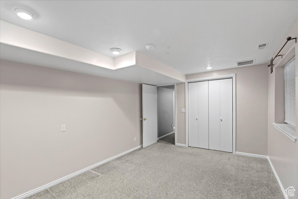 Unfurnished bedroom with light carpet and a closet