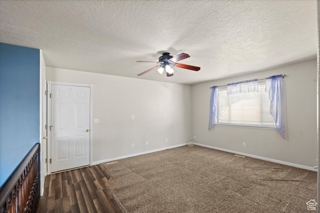 Empty room with ceiling fan, a textured ceiling, and wood finished floors