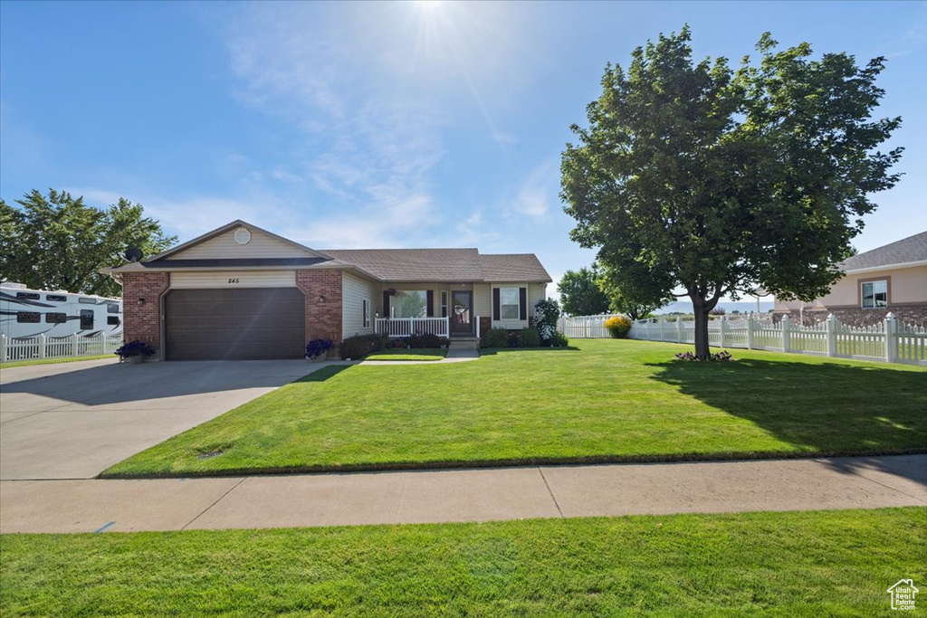 Ranch-style home with brick siding, covered porch, an attached garage, and concrete driveway