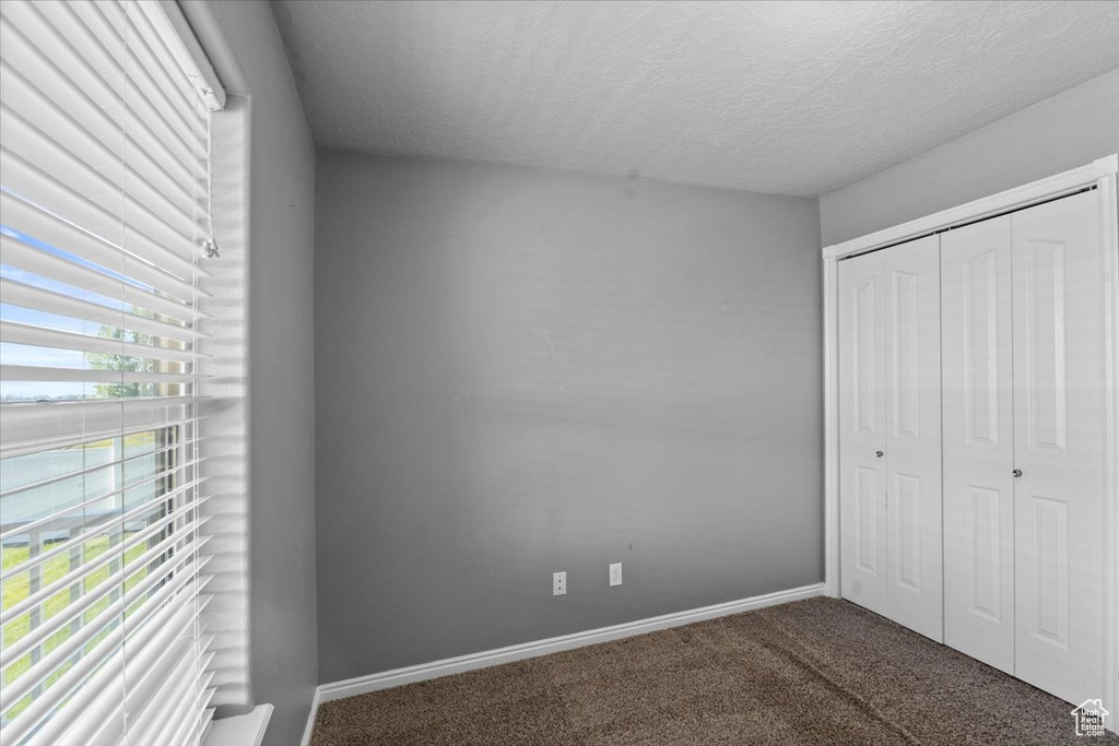 Unfurnished bedroom with carpet flooring, a textured ceiling, and a closet