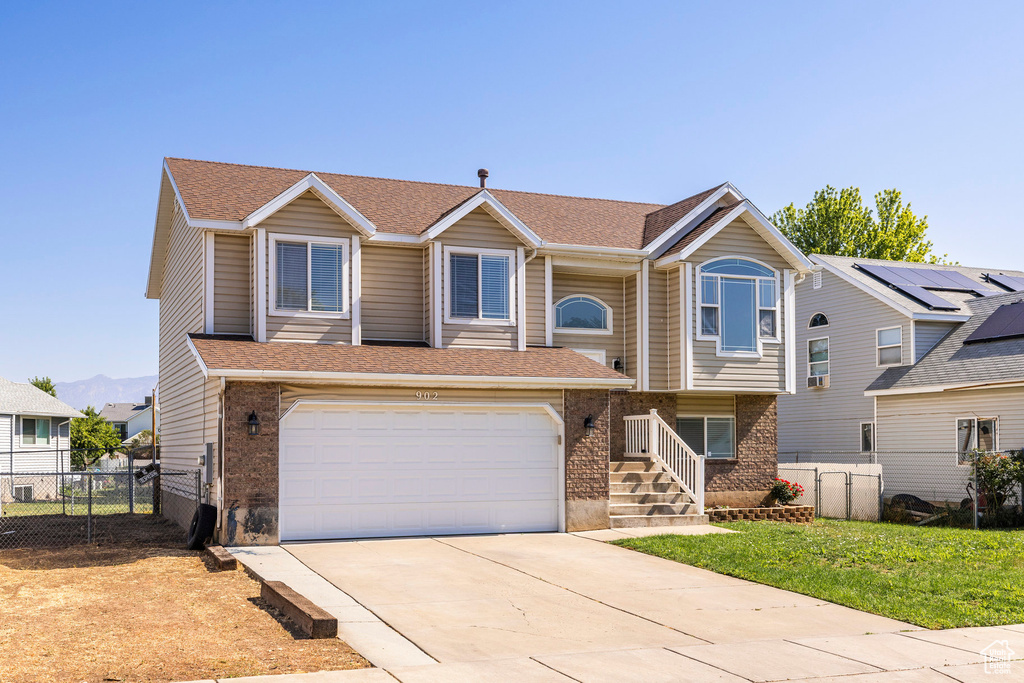 View of front of house with brick siding, concrete driveway, an attached garage, and roof with shingles