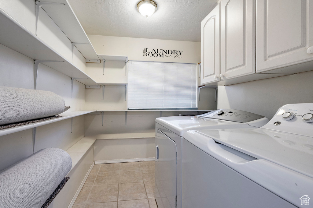 Laundry room featuring cabinet space, washing machine and dryer, and light tile patterned flooring