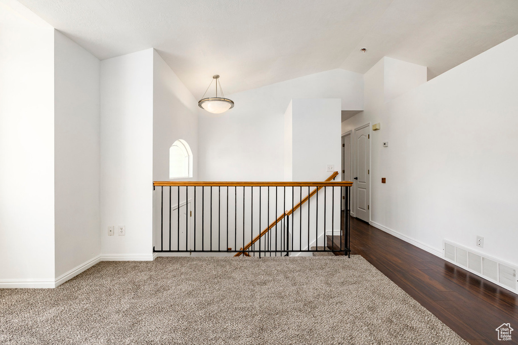 Empty room with lofted ceiling and wood finished floors