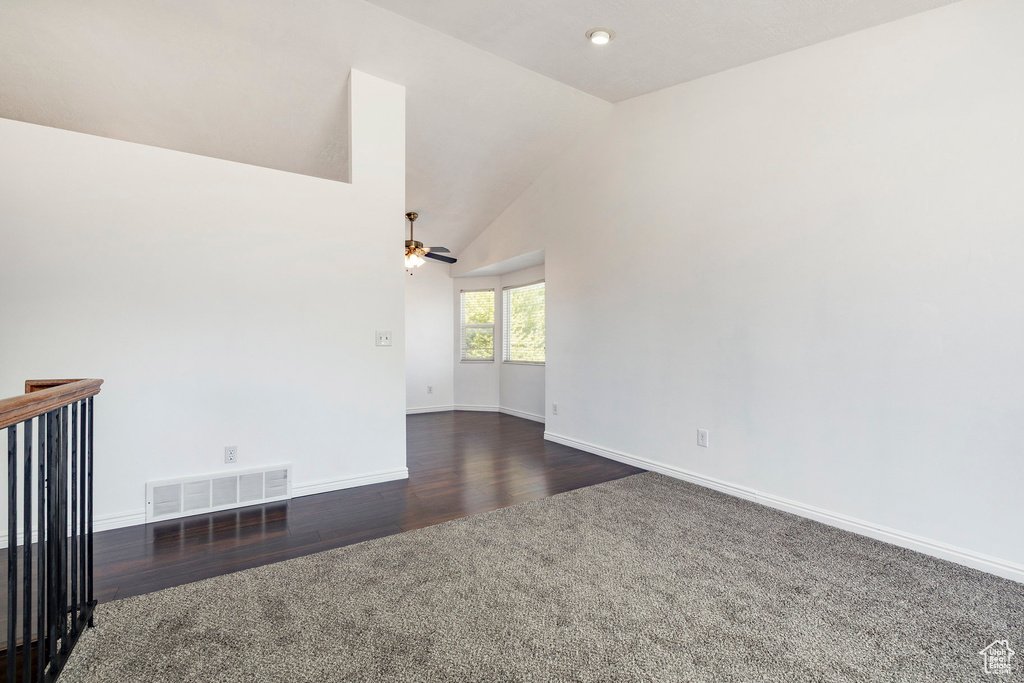 Unfurnished room with carpet flooring, a ceiling fan, vaulted ceiling, and wood finished floors