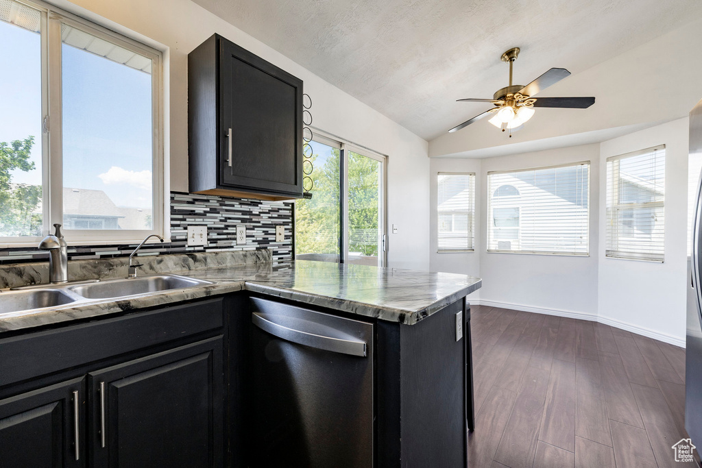 Kitchen with stainless steel dishwasher, dark cabinets, vaulted ceiling, a ceiling fan, and backsplash