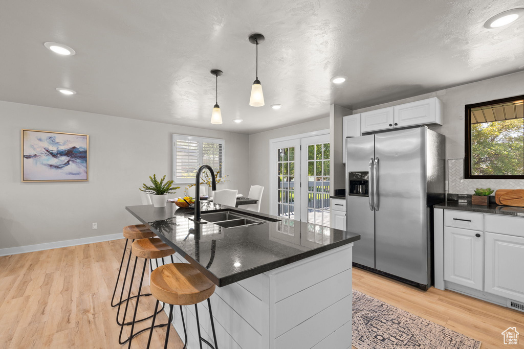 Kitchen with stainless steel fridge with ice dispenser, white cabinets, plenty of natural light, light wood-type flooring, and recessed lighting