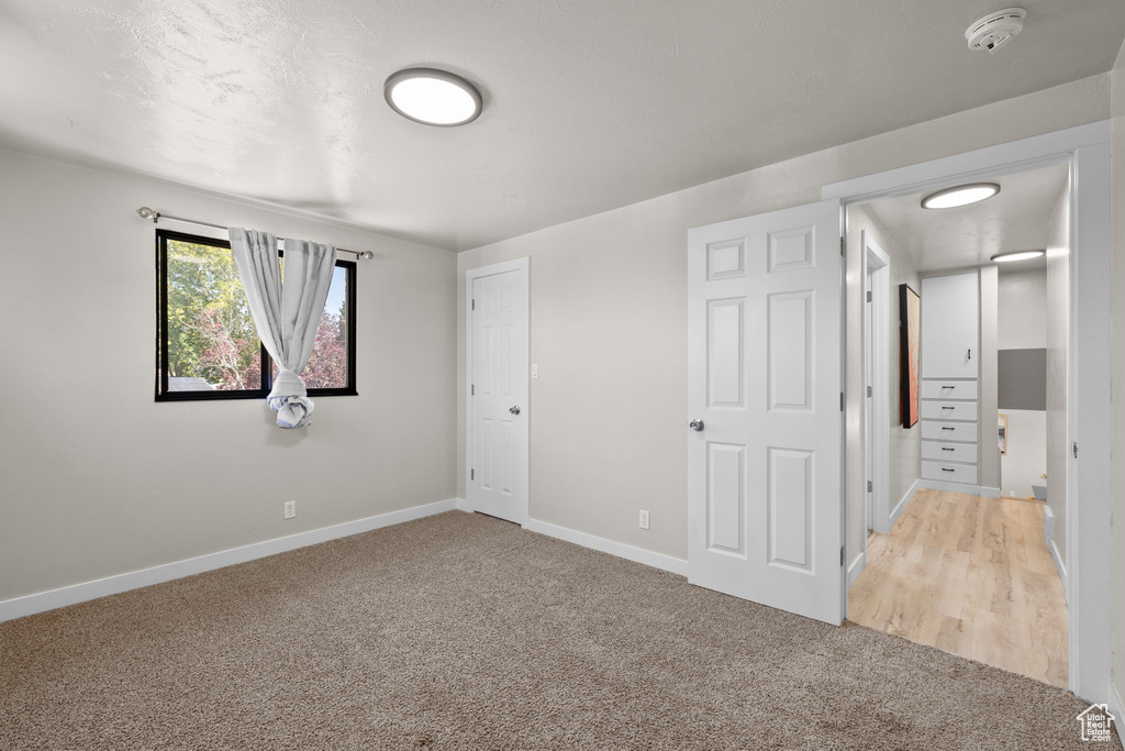 Unfurnished bedroom with light colored carpet and baseboards