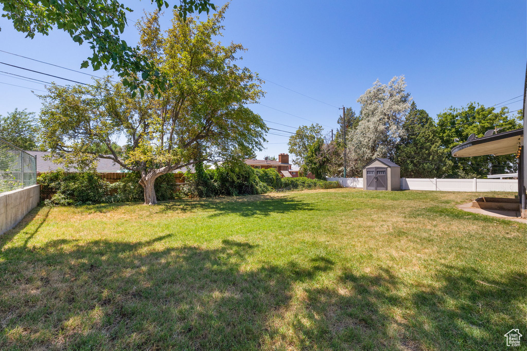 Fenced backyard featuring a storage shed