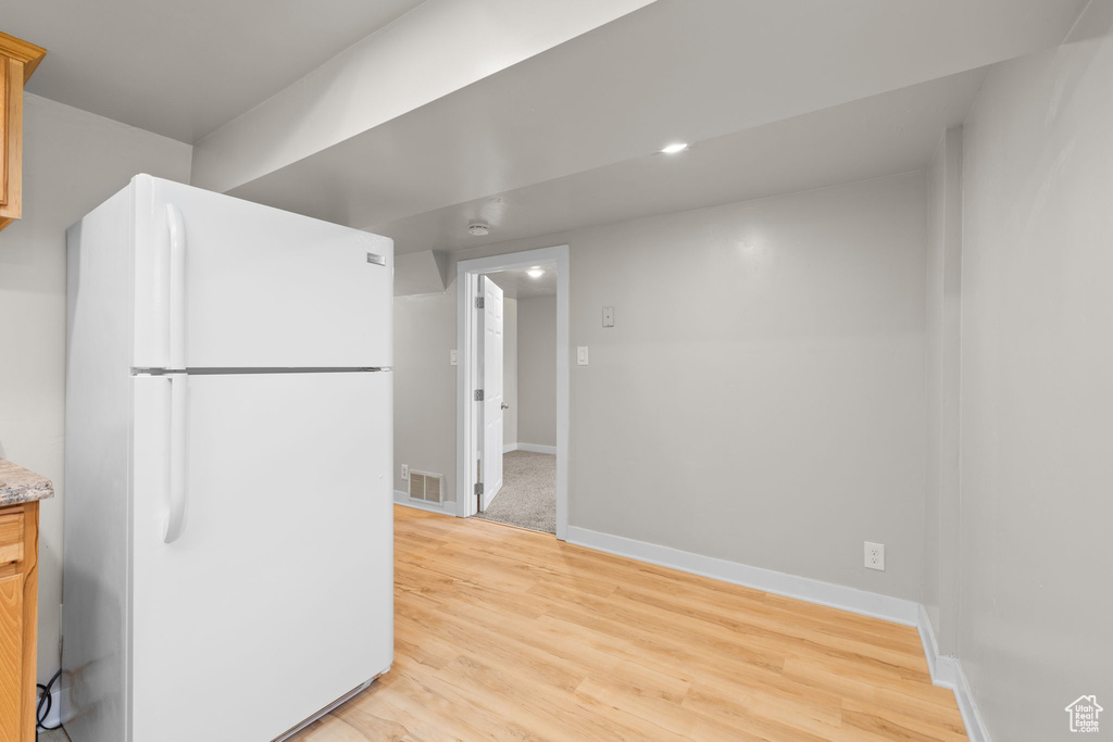 Kitchen with freestanding refrigerator and light wood-style flooring
