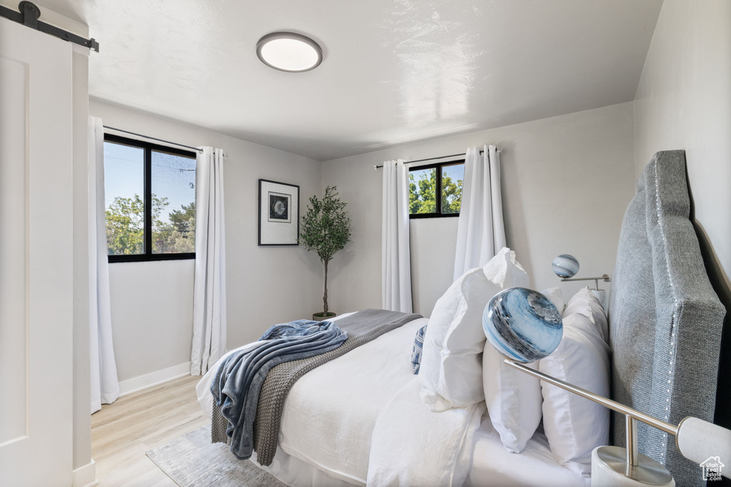 Bedroom with a barn door and wood finished floors