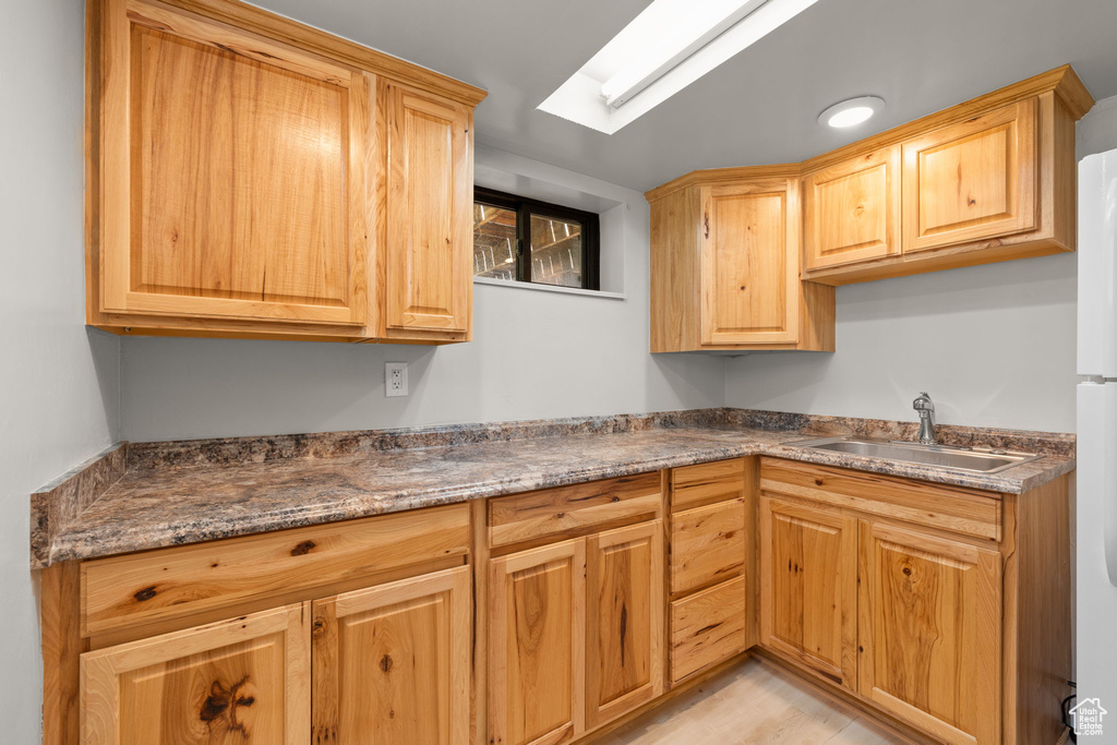 Kitchen with light brown cabinets, light wood-type flooring, and dark countertops