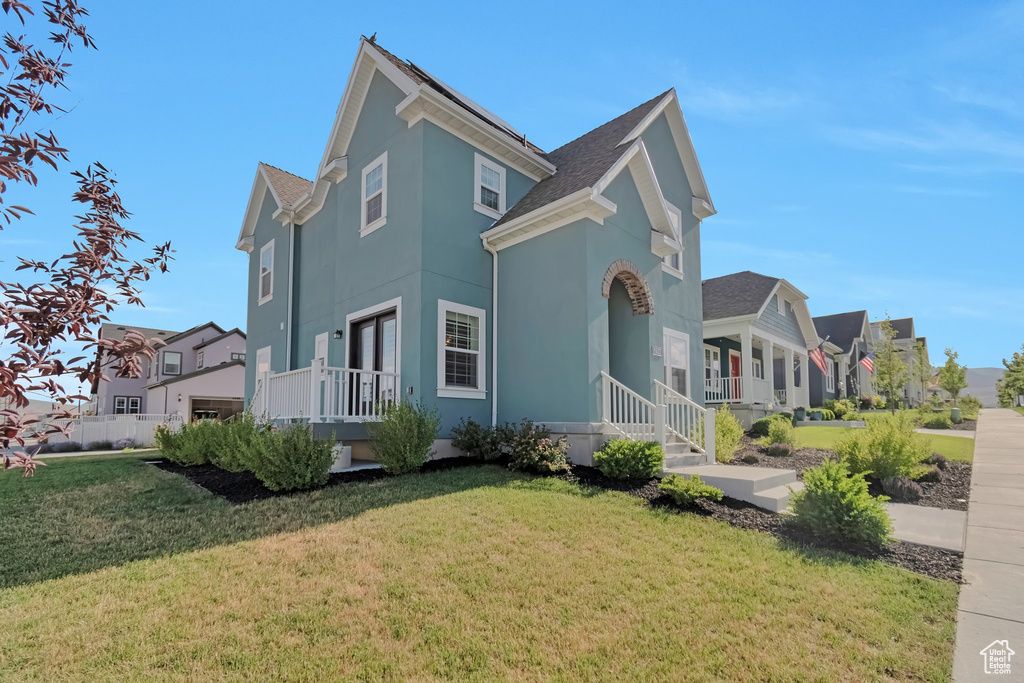 View of front of home with a front yard, stucco siding, a shingled roof, and a residential view