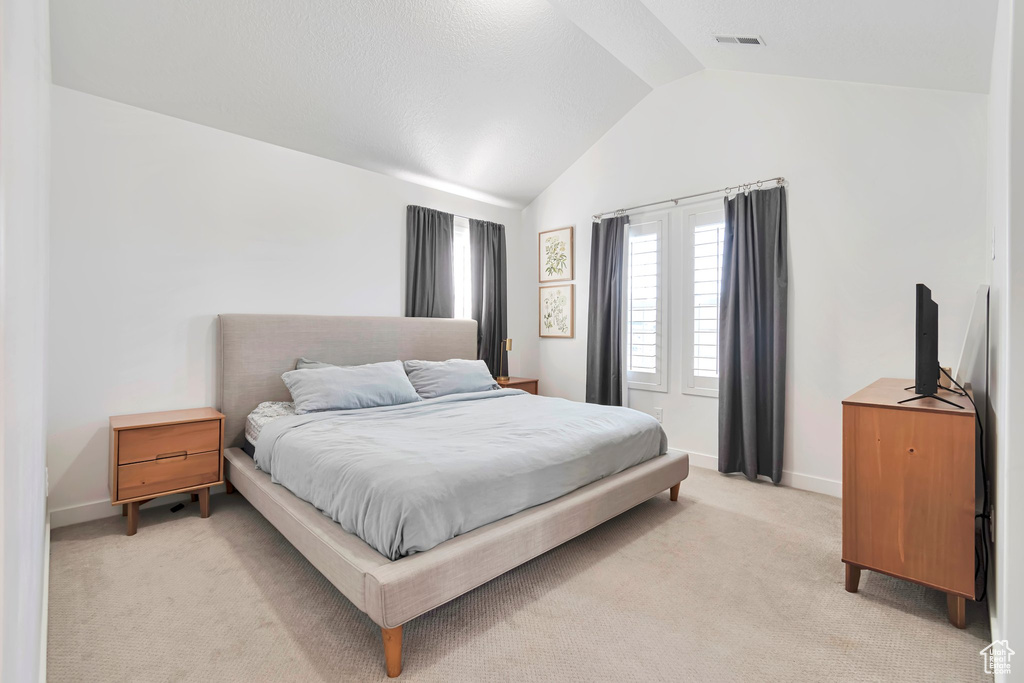 Bedroom featuring lofted ceiling and light colored carpet