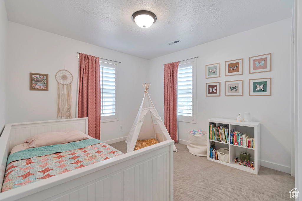 Carpeted bedroom with a textured ceiling and baseboards