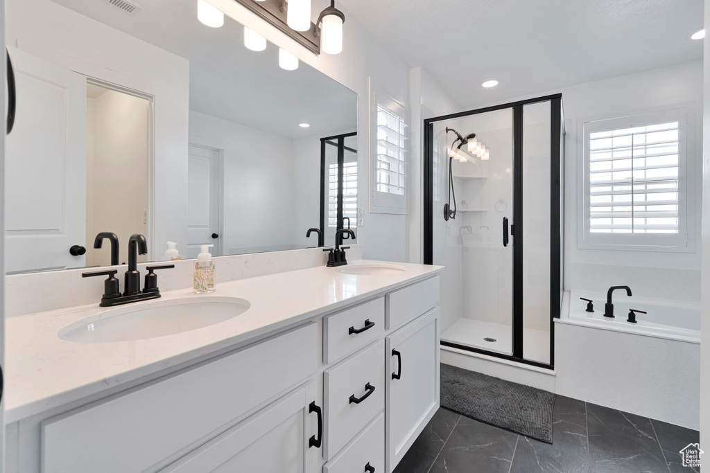 Bathroom with healthy amount of natural light, a stall shower, double vanity, a bath, and recessed lighting