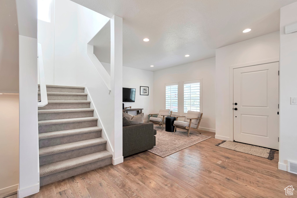 Foyer with wood finished floors, stairway, and recessed lighting