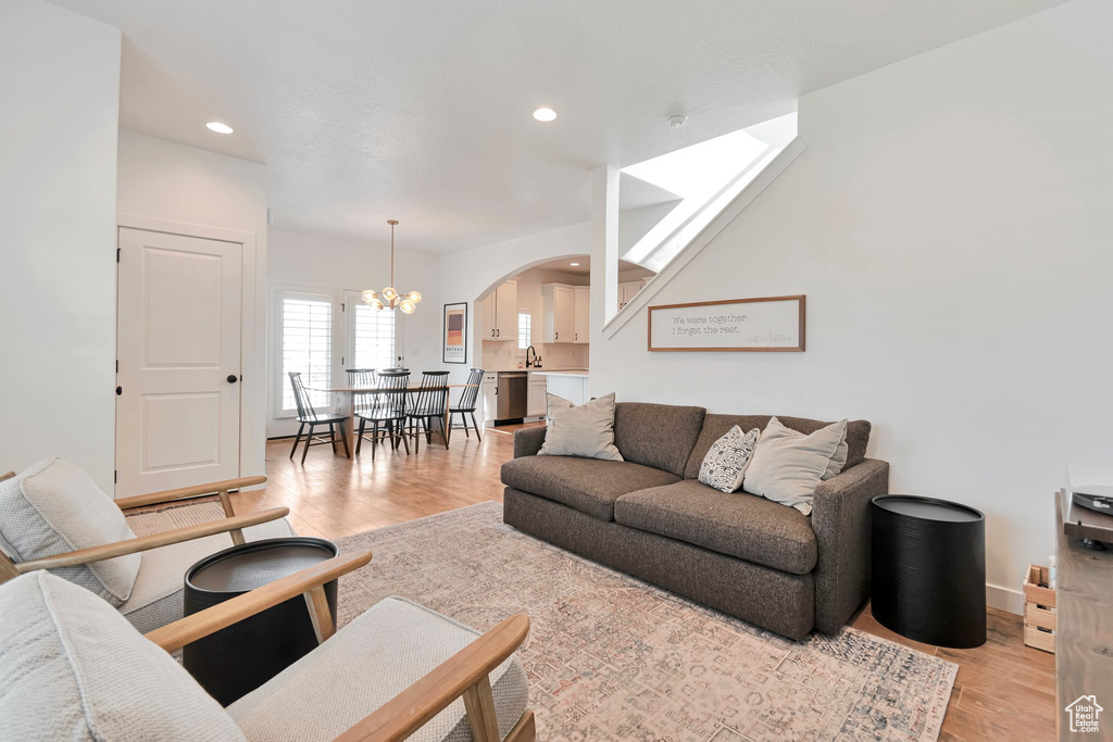 Living area featuring arched walkways, light wood-type flooring, recessed lighting, and a chandelier