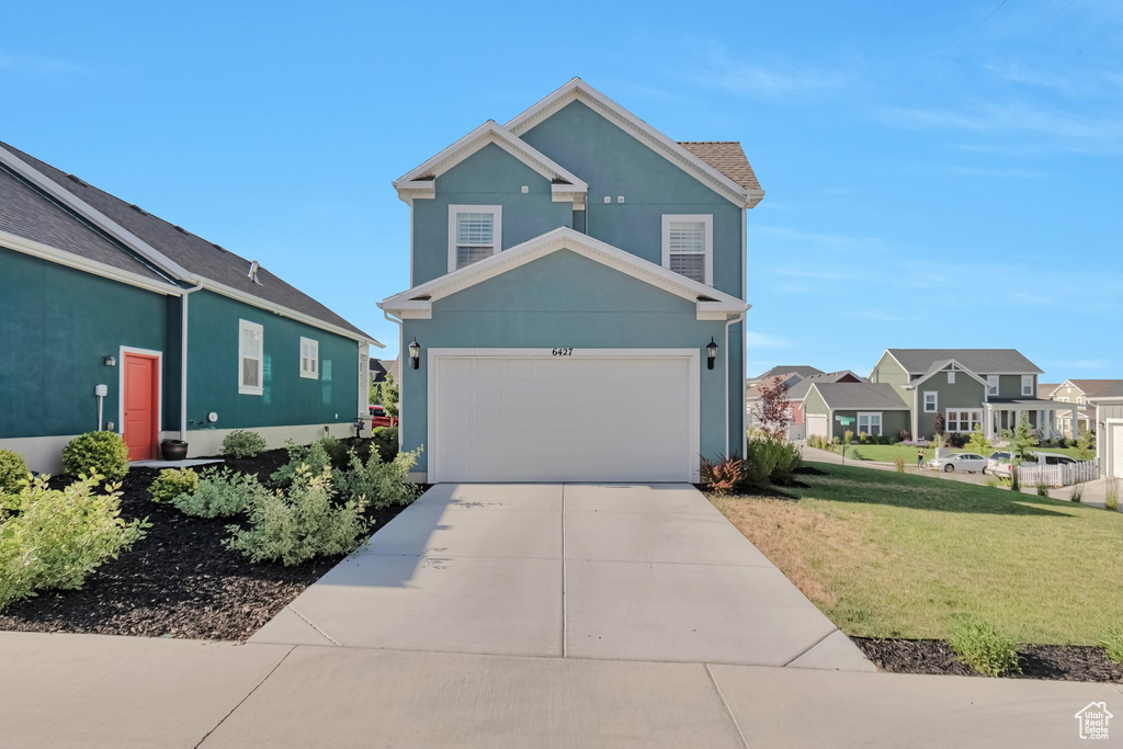 View of front of home with concrete driveway, a front yard, stucco siding, and a residential view