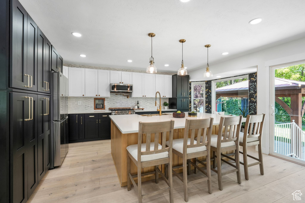 Kitchen with stainless steel microwave, light countertops, freestanding refrigerator, a breakfast bar, and backsplash