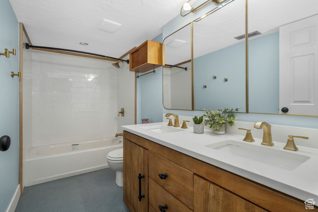Bathroom featuring double vanity, shower / bath combination, and tile patterned flooring