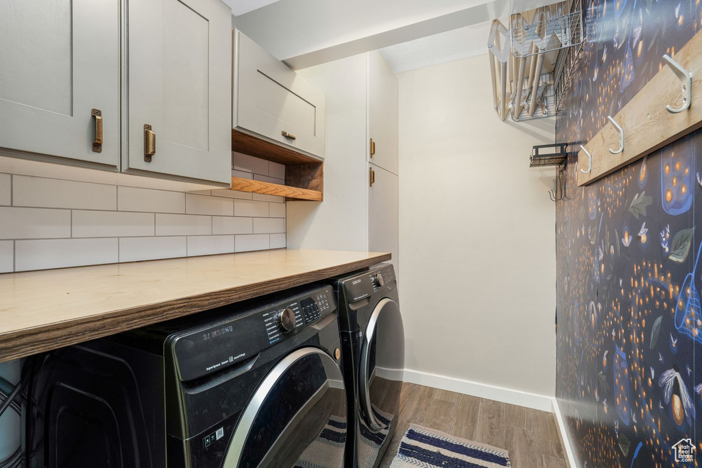 Laundry area featuring washing machine and dryer, wood finished floors, and cabinet space