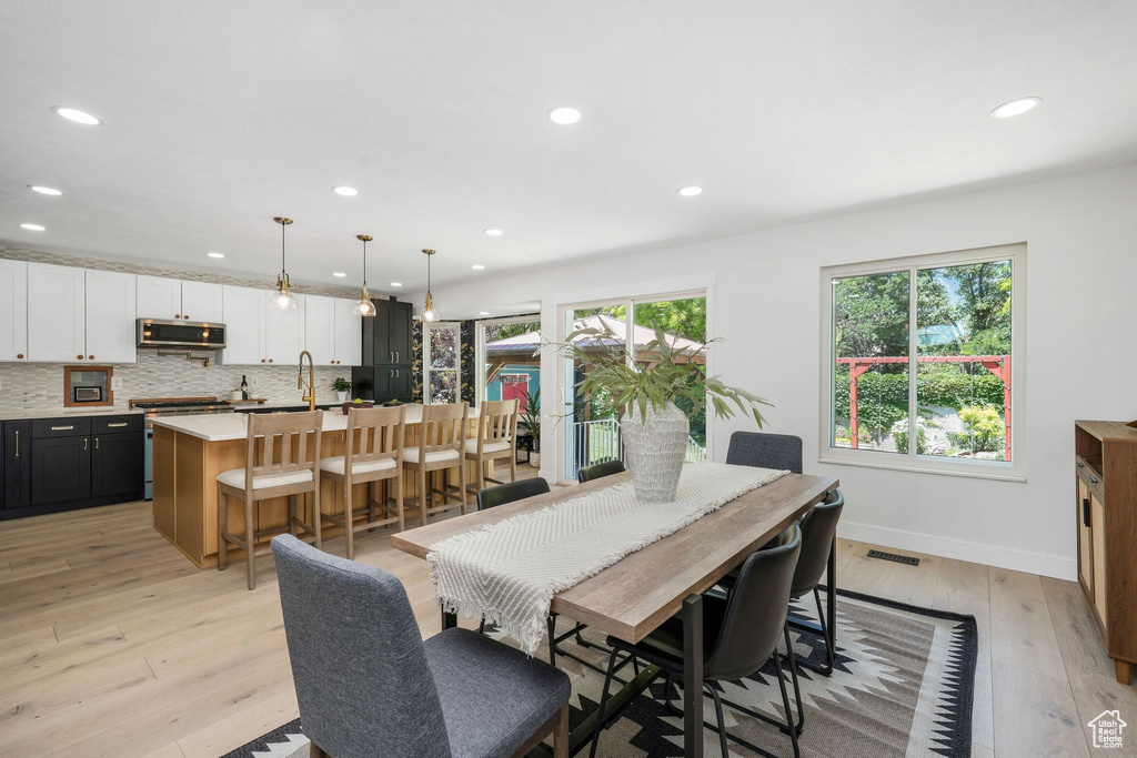 Dining room with healthy amount of natural light, light wood finished floors, and recessed lighting