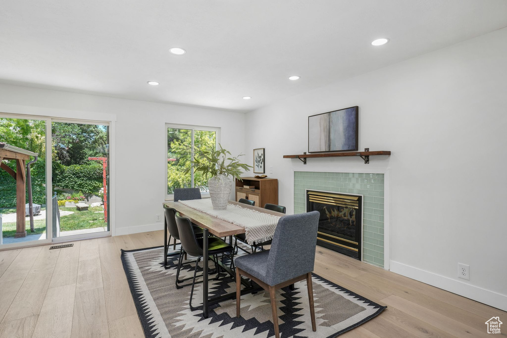 Dining area featuring a tile fireplace, recessed lighting, and light wood-type flooring