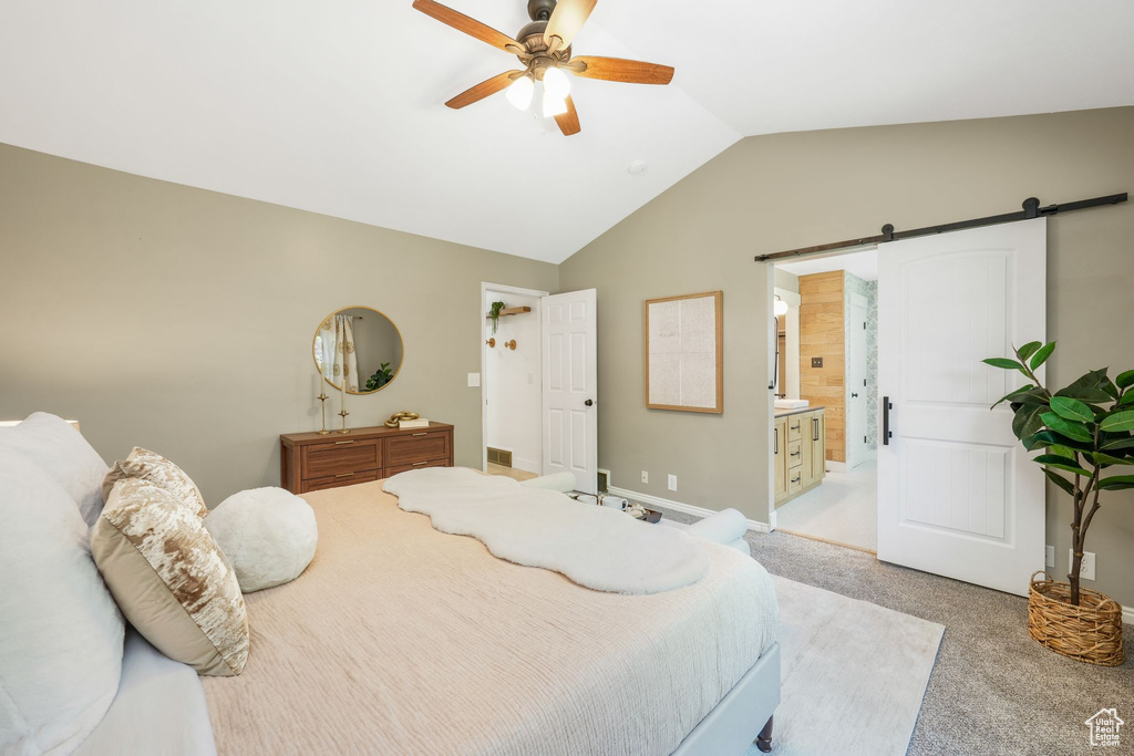 Bedroom featuring a barn door, vaulted ceiling, light colored carpet, ceiling fan, and connected bathroom