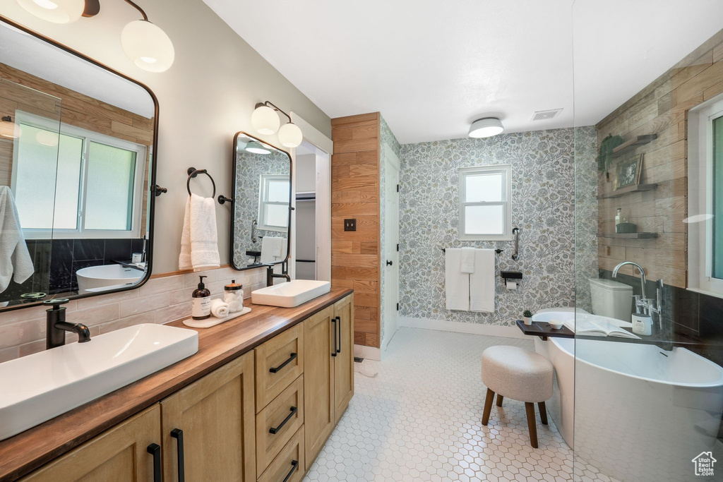 Full bath with double vanity, a freestanding tub, and a tile shower