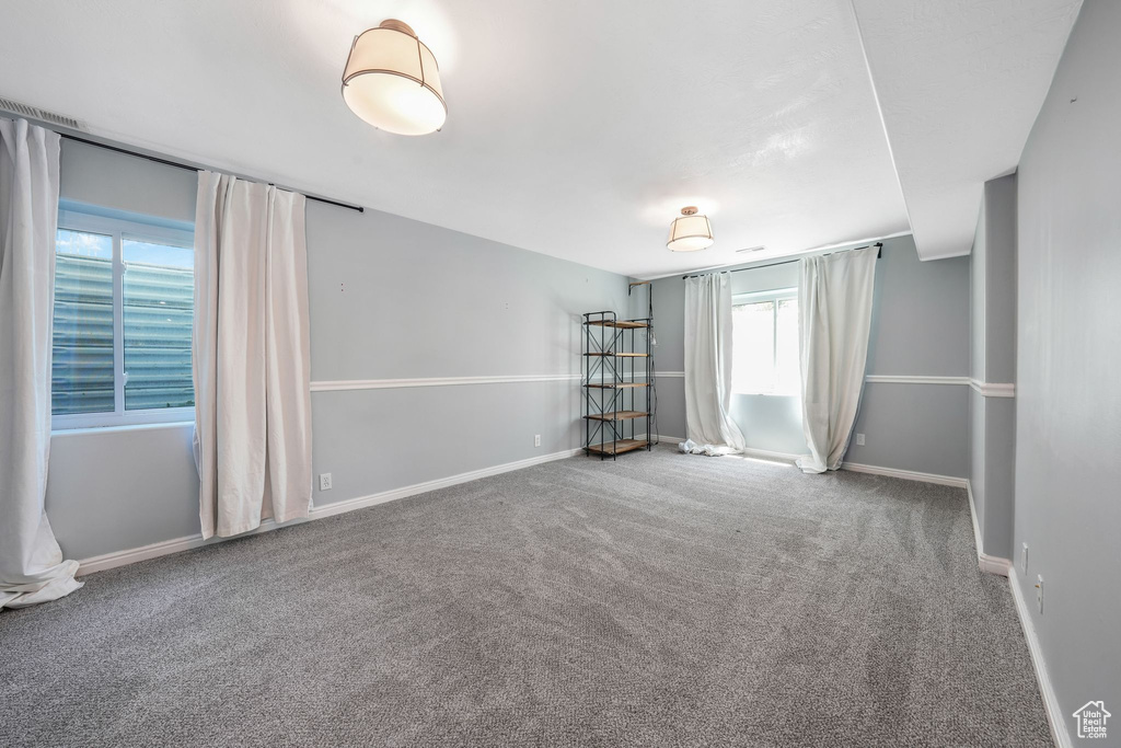 Carpeted spare room featuring baseboards