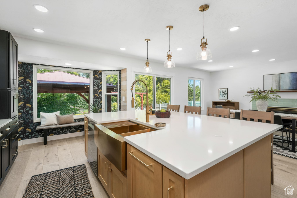 Kitchen with light countertops, an island with sink, recessed lighting, decorative light fixtures, and a breakfast bar area