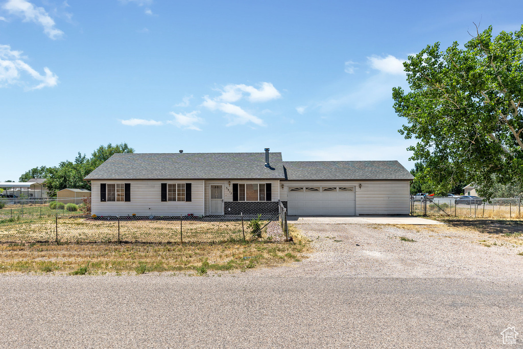 Ranch-style house featuring driveway, an attached garage, and a fenced front yard