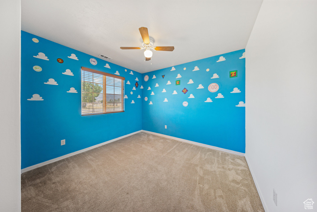 Empty room featuring a ceiling fan and carpet flooring