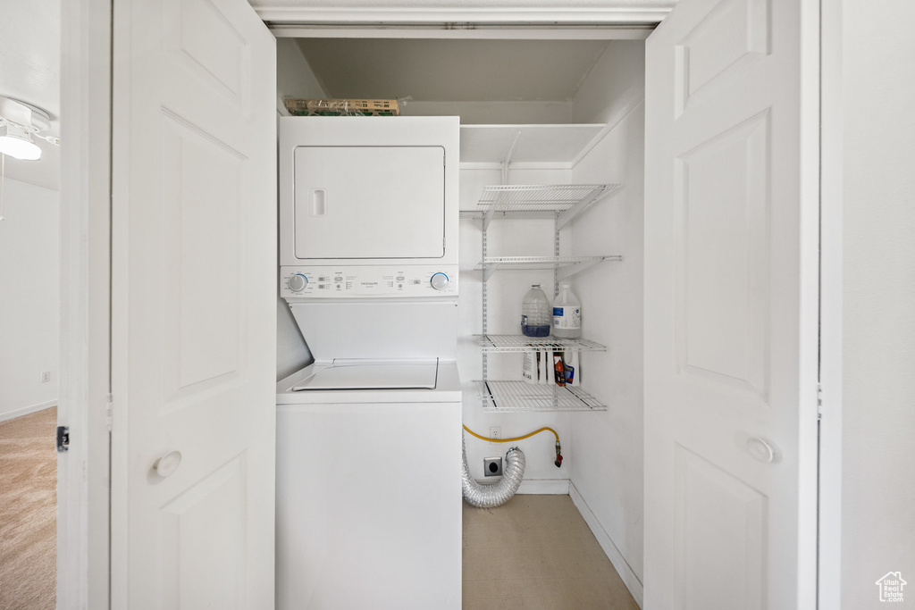 Washroom with stacked washing machine and dryer and baseboards