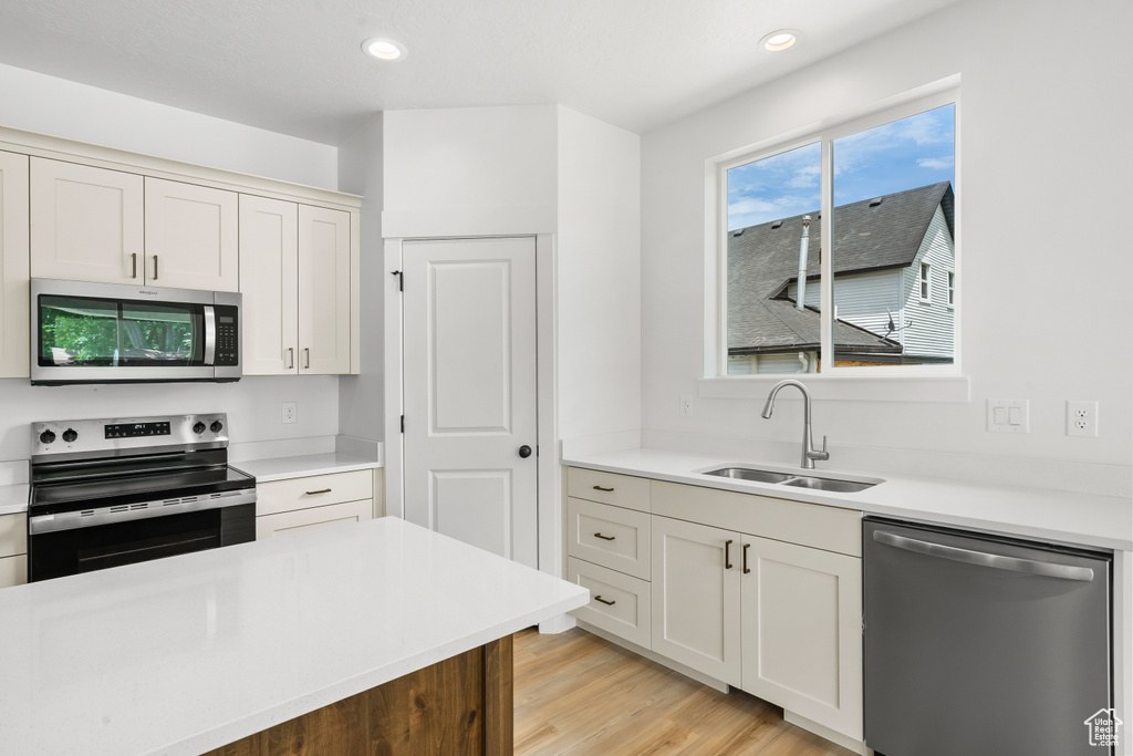 Kitchen featuring appliances with stainless steel finishes, light countertops, light wood finished floors, recessed lighting, and white cabinets