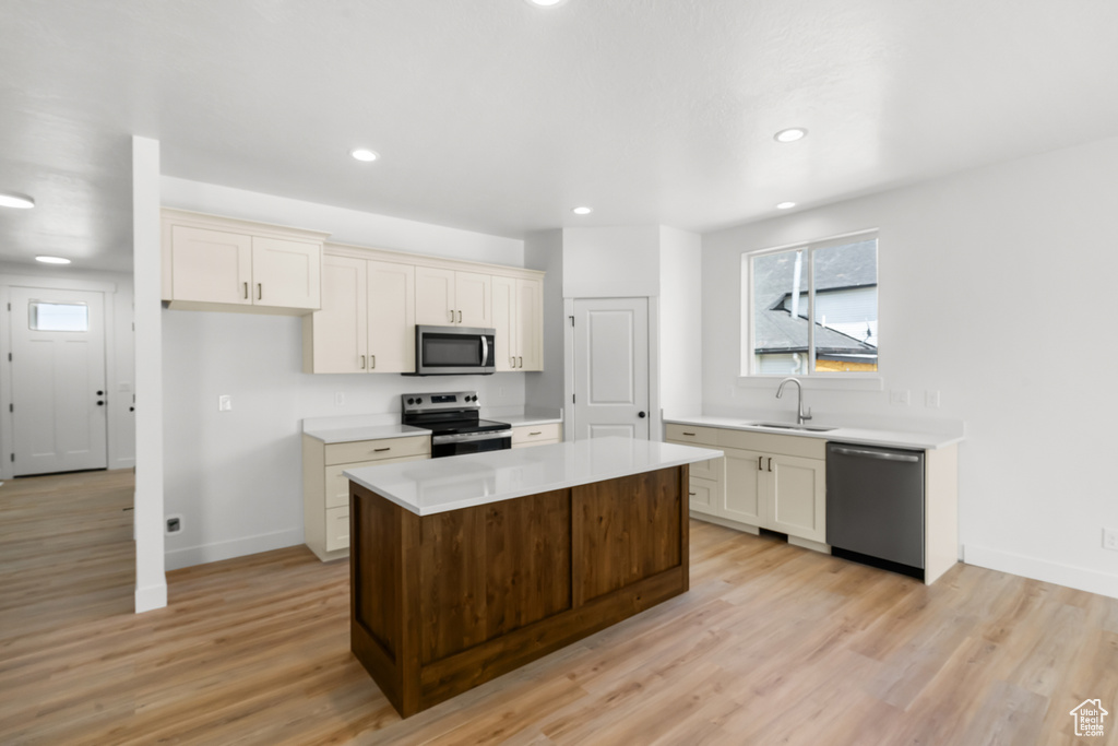 Kitchen with appliances with stainless steel finishes, light countertops, light wood-style floors, a kitchen island, and recessed lighting